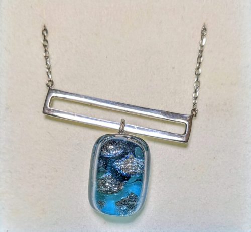 Dichroic glass pendant in an open sterling silver rectangle.
